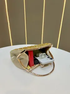 Detailed view of a gold rhinestone evening clutch handbag, showing interior capacity on white table.
