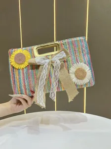 Detail view of colorful woven straw handbag featuring lace bow, metal handle and floral decor.
