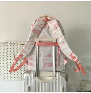 Détail de sac à dos d'école imprimé rose avec bretelles et sangle de valise sur valise.