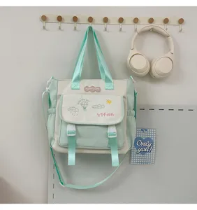 Détail de sac cabas en toile vert menthe et blanc cassé avec poche et motif.