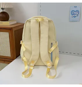 Sac à dos d'écolier jaune clair, vue arrière montrant les bretelles et la poche zippée.