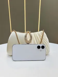 Primo piano di una pochette da sera plissata color champagne con chiusura in strass.