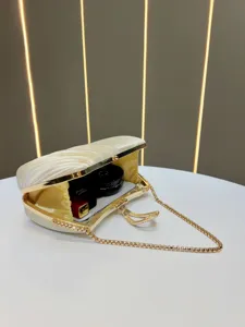 Dettaglio di elegante borsa da sera plissettata con chiusura strass e catena dorata.