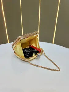 Detailed view of luxury gold rhinestone evening clutch bag with chain strap and satin lining.