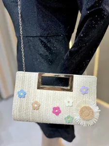 Detailed close-up of straw woven crossbody bag showcasing handmade floral crochet and metal handle.