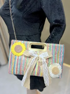 Detailed view of a colorful woven straw shoulder bag with chain strap and flower bow decor.