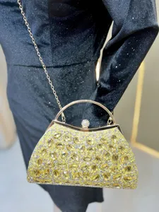 Luxury crystal evening bag detail, sparkling yellow rhinestones with gold chain strap.