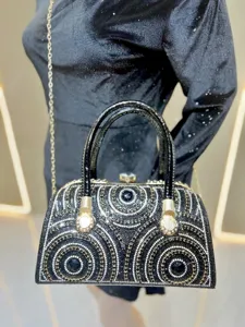 Exquisite rhinestone evening bag detail, sparkling crystals and black patent leather handle.