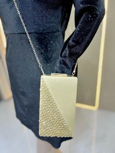 Gold rhinestone evening clutch bag detail, sparkling diamond crossbody chain purse closeup.