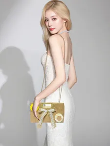 Detailed view of stylish woven straw shoulder bag with chain strap and bow decoration.