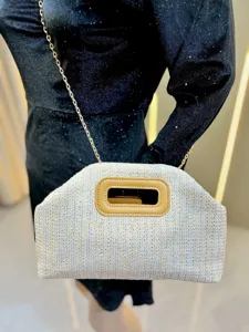 Detailed view of the stylish woven straw handbag with a cutout brown handle and chain strap.