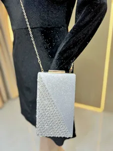 Detailed view of silver rhinestone evening clutch bag with gold chain strap and metal clasp.