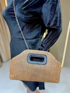 Detailed view of the stylish straw woven crossbody bag with chain strap and black handle.
