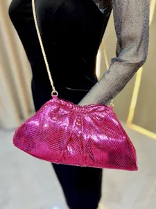 Détail de pochette en similicuir serpent rose métallisé, sac de soirée élégant avec chaîne.