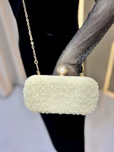 Elegant pearl evening clutch detail, featuring gold chain strap and sparkling rhinestone clasp.