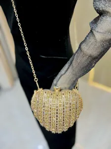 Detailed shot of glittering crystal heart evening clutch bag with golden chain strap for women.