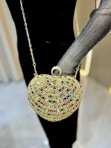 Primo piano della pochette da sera a cuore con strass colorati e catena dorata brillante ed elegante.