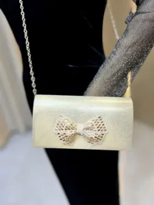 Vintage gold glitter clutch bag with rhinestone bow detail, elegant evening handbag.
