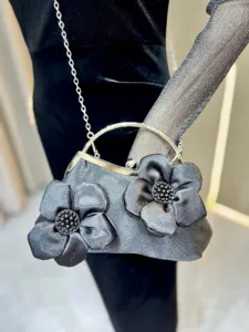 Vue rapprochée détaillée de l'élégant sac de soirée avec fleurs et bandoulière chaîne.