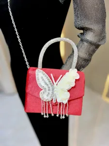 Red velvet rhinestone butterfly evening bag detail shot, elegant crystal chain crossbody handbag.