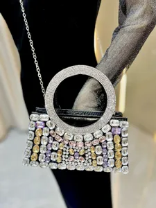 Close-up of luxury rhinestone evening bag with circular crystal handle and sparkling multicolor gems.
