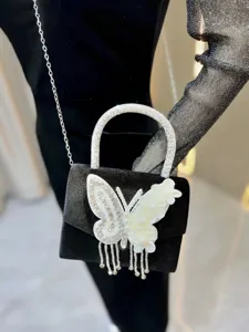 Detail of black velvet evening bag with rhinestone handle and white butterfly fringe charm.