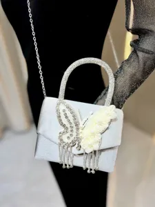 Detail shot of silver rhinestone evening bag with butterfly tassel and pearl flower design.