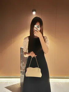 Elegant evening clutch bag with metal frame clasp and chain strap detail in scene view.