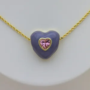 Primo piano dettagliato del ciondolo a cuore in smalto viola con zircone rosa e ottone.