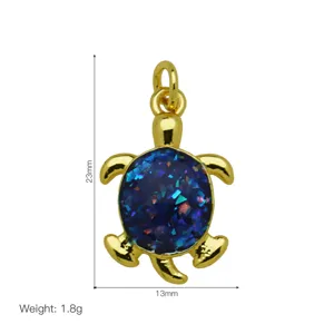 Gold-plated turtle pendant detail view showing 23mm height, 13mm width, and blue glitter inlay.
