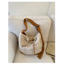 Détail de sac bandoulière en polaire duveteuse, sangle contrastée, fourre-tout spacieux.