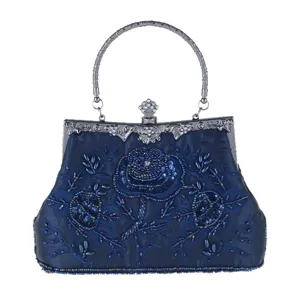 Detail view of dark blue evening bag with intricate bead embroidery, metal handle and clasp.