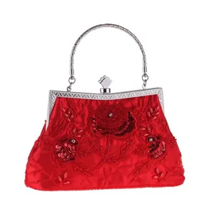 Close-up detail of the red evening beaded clutch showing exquisite floral embroidery and handle.