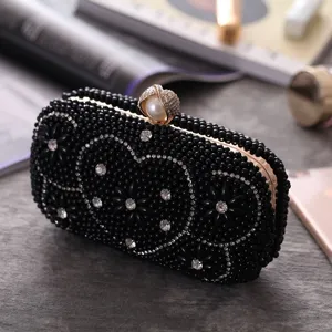 Detailed shot of black beaded evening clutch bag with rhinestones and pearl clasp, elegant.