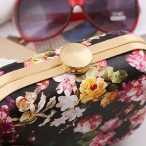 Floral print hard shell evening clutch bag detail closeup, elegant gold frame design.