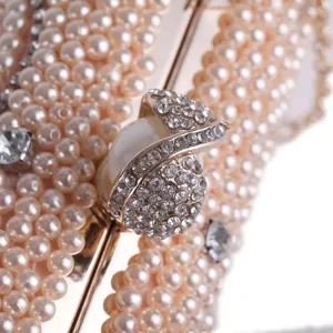 Close-up detail of luxury pearl evening clutch bag with sparkling rhinestone clasp decoration.