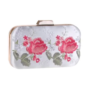 Detailed view of the satin evening clutch with pink rose embroidery and gold hardware.