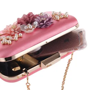 Close up of pink satin evening clutch featuring floral pearl decor and open interior view.