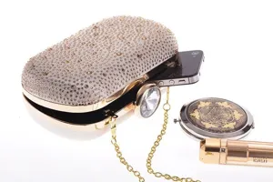 Close-up view of luxury rhinestone acrylic evening clutch bag with gold chain strap detail.