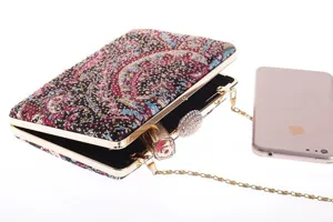 Detailed view of rhinestone evening clutch bag with metallic frame and paisley print pattern.