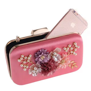 Pink satin evening clutch purse detail showcasing artificial floral and pearl decorations close-up.