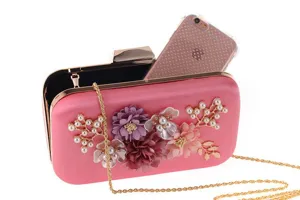 Detail shot of pink evening clutch bag adorned with pearls and floral decorations, chic design.