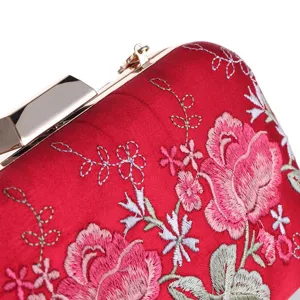 Red satin evening clutch bag detail featuring delicate pink rose floral embroidery and gold metal frame.