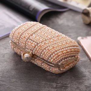 Close-up detail of a handmade pearl and rhinestone evening clutch bag with metal clasp.