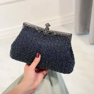 Close-up detail of the elegant navy blue beaded evening clutch bag with ornate metal frame clasp.