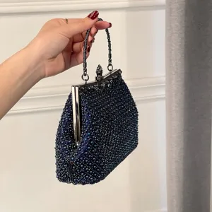 Close-up detail of the elegant navy blue beaded evening clutch bag with metal frame clasp.