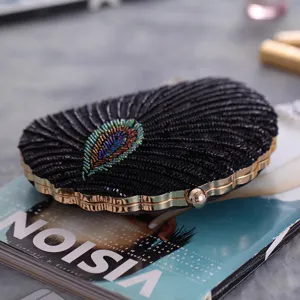 Black sequin beaded evening clutch bag detail with colorful peacock feather and gold metal frame.