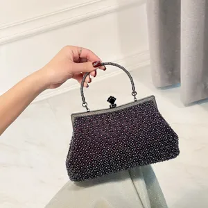 Close-up detail of the elegant dark purple beaded evening clutch bag with metallic frame.