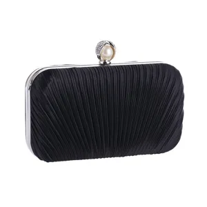 Elegant black pleated clutch bag detail featuring a sparkling pearl rhinestone clasp and metal frame.