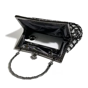 Black beaded evening clutch bag with metal frame handle, elegant accessory for parties and banquets.
